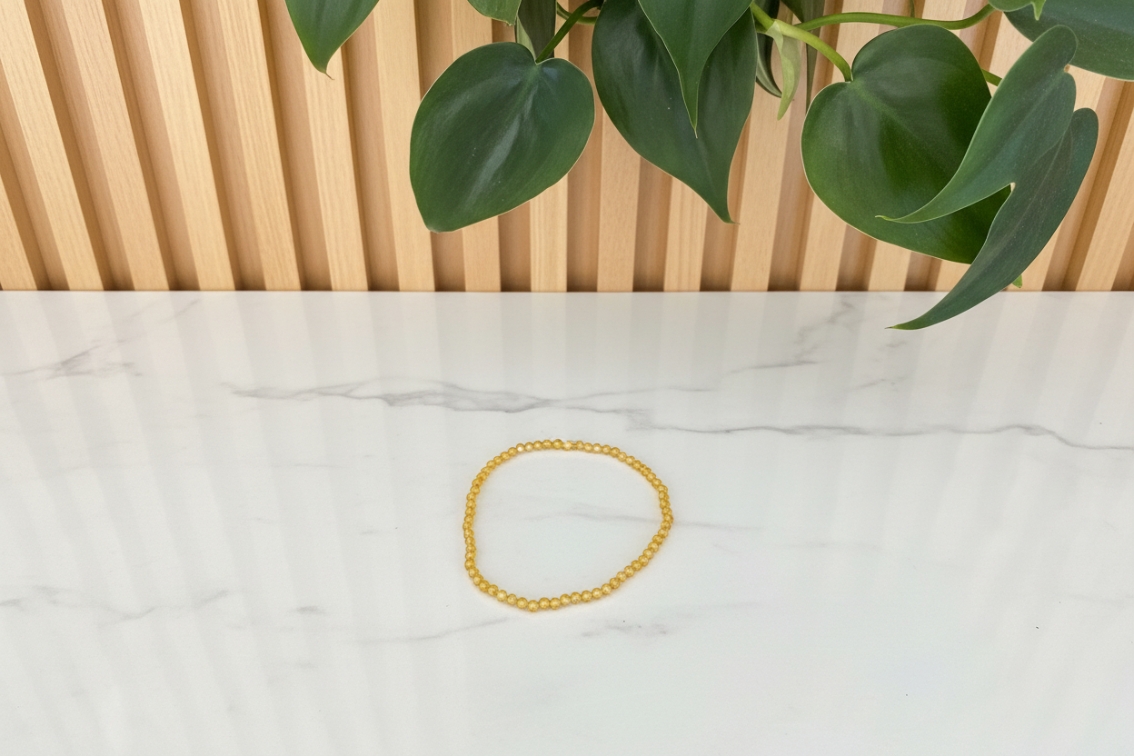 Yellow bracelet on a white counter with a plant in the background