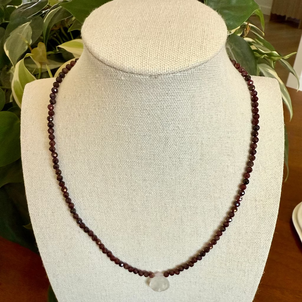 red beaded necklace on a white bust