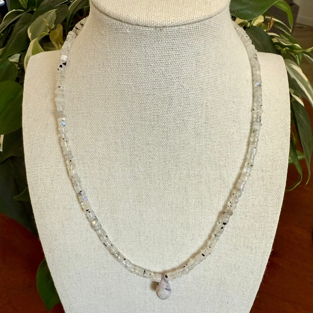 Necklace on a mannequin bust with a plant in the background