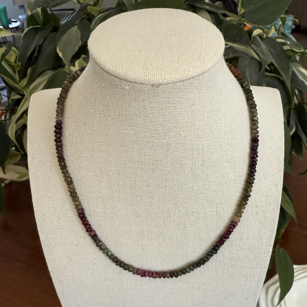 Necklace on a mannequin bust with a plant in the background