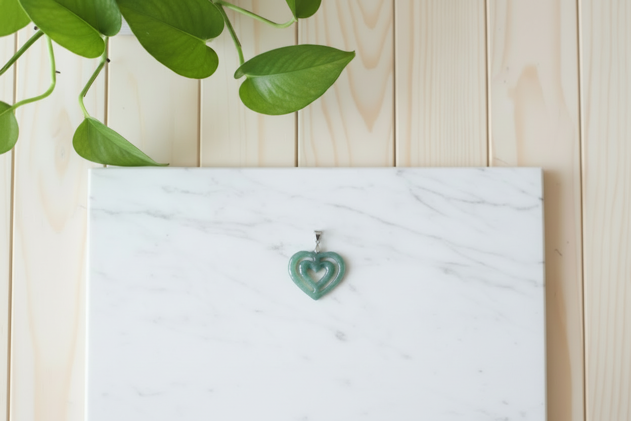 White marble counter with a green jade heart pendant on a wooden surface