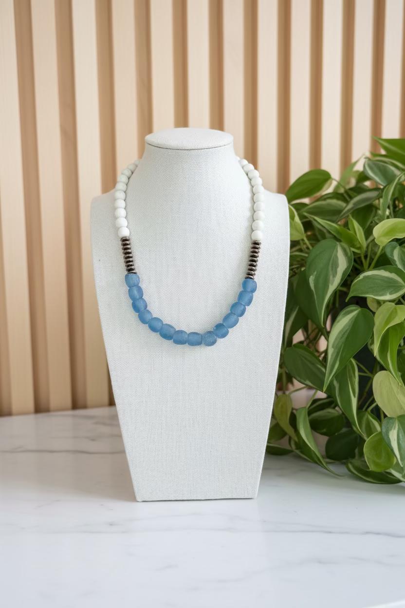 African glass bead necklace on a white bust against a blurred indoor background