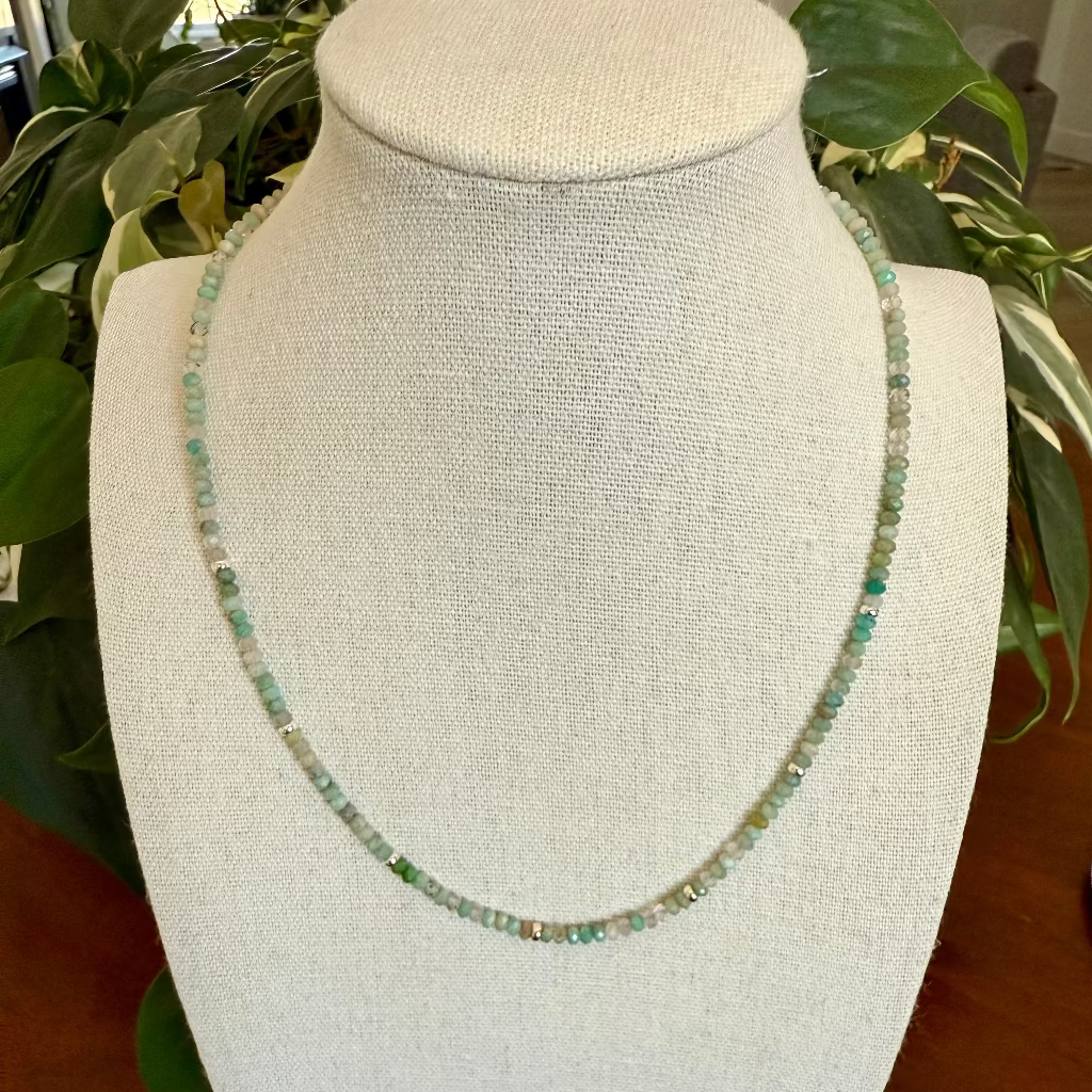 Necklace on a white bust with greenery in the background