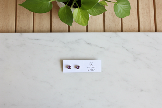 Pair of earrings on a white card with 'Willow & Fern' branding on a white counter with a plant