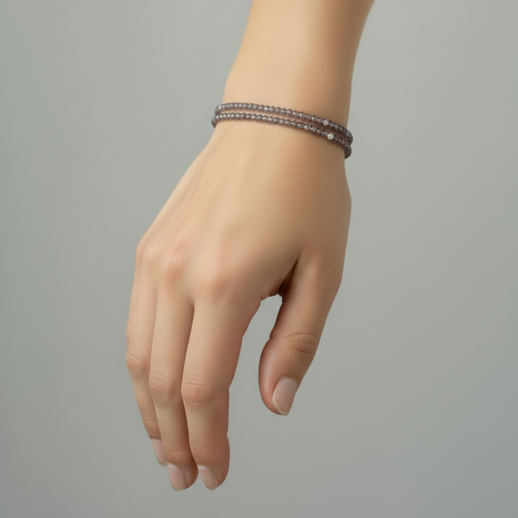 Hand wearing a bracelet on a gray background