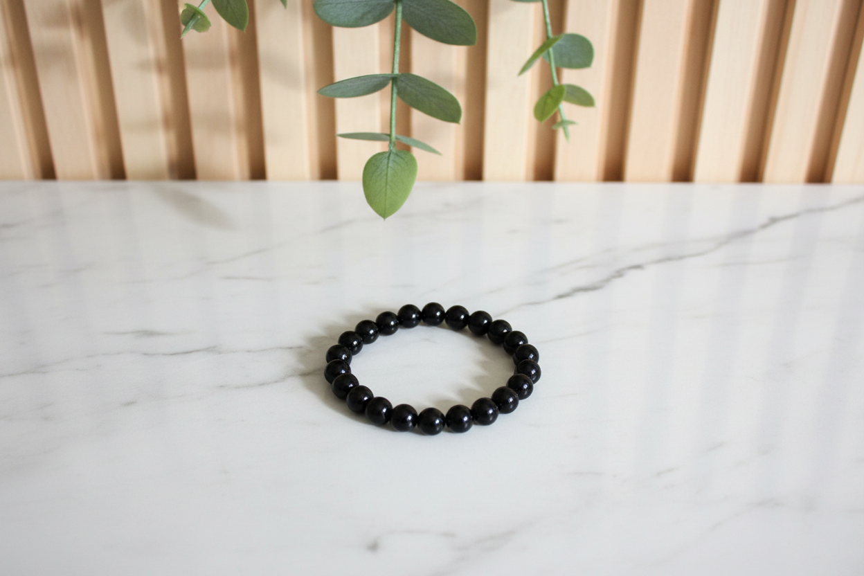 Black beaded bracelet on a white counter with a plant in the background
