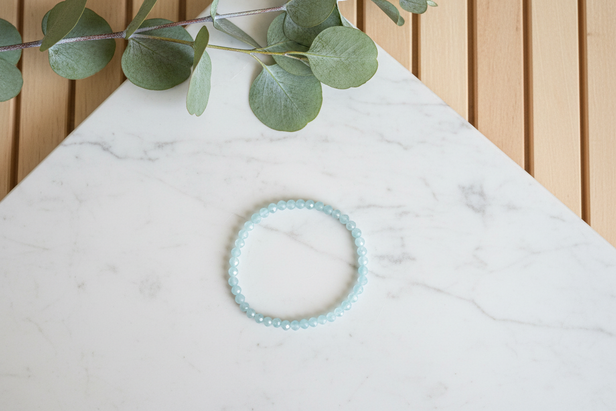 White counter with a blue bracelet and green leaves in the background