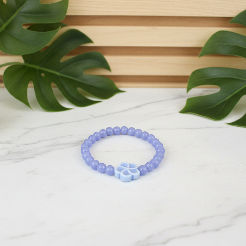 Blue bracelet with floral design on a white counter with a plant in the background
