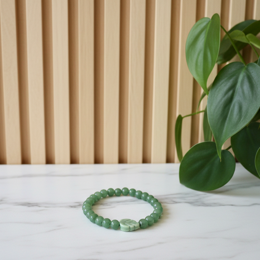 Green beaded bracelet on white counter with a plant in the background