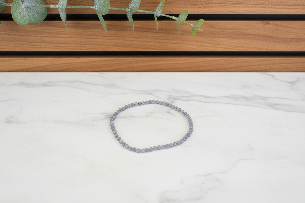 Gray beaded bracelet on a white counter with a plant in the background