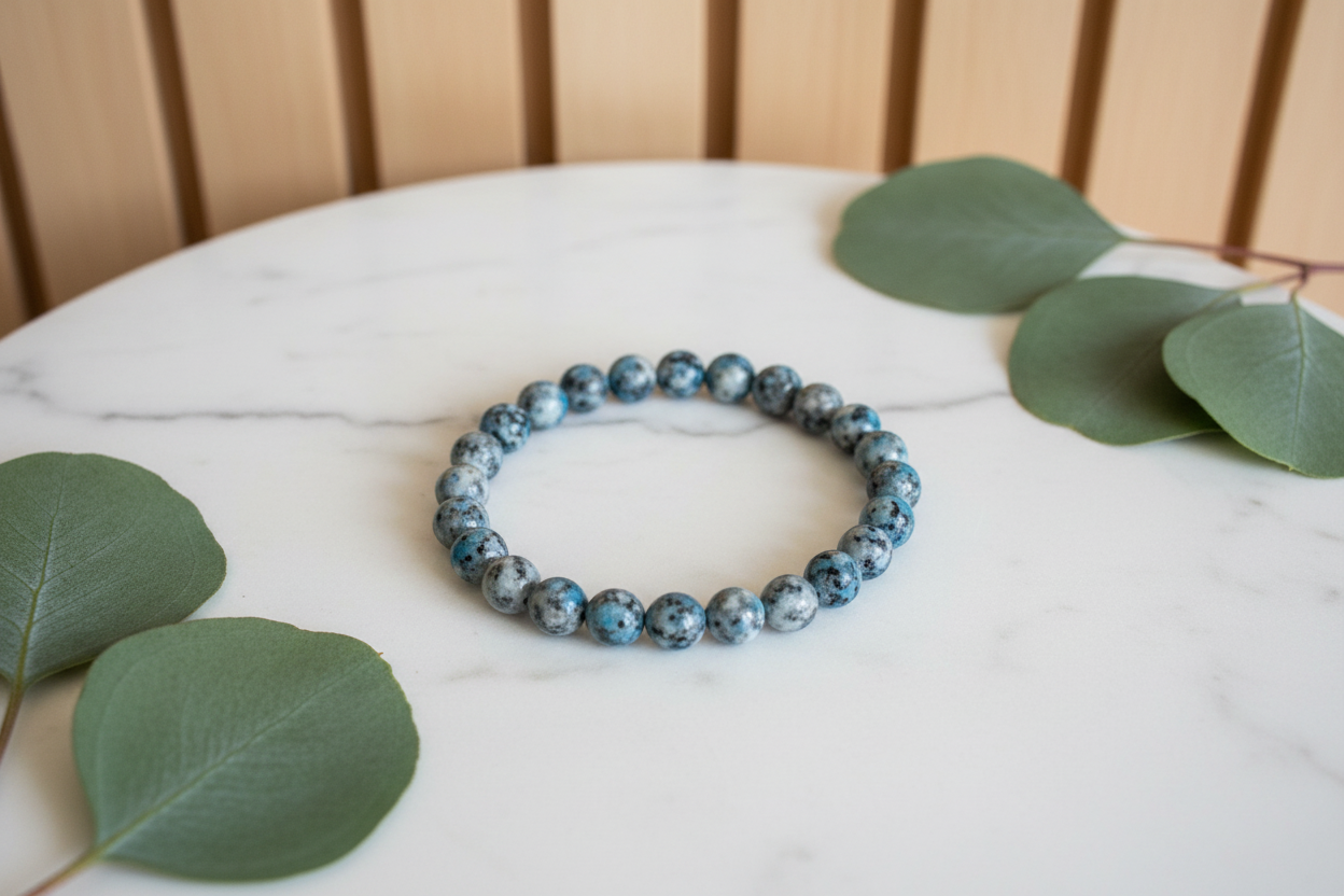 Blue beaded bracelet on a white counter with green leaves in the background