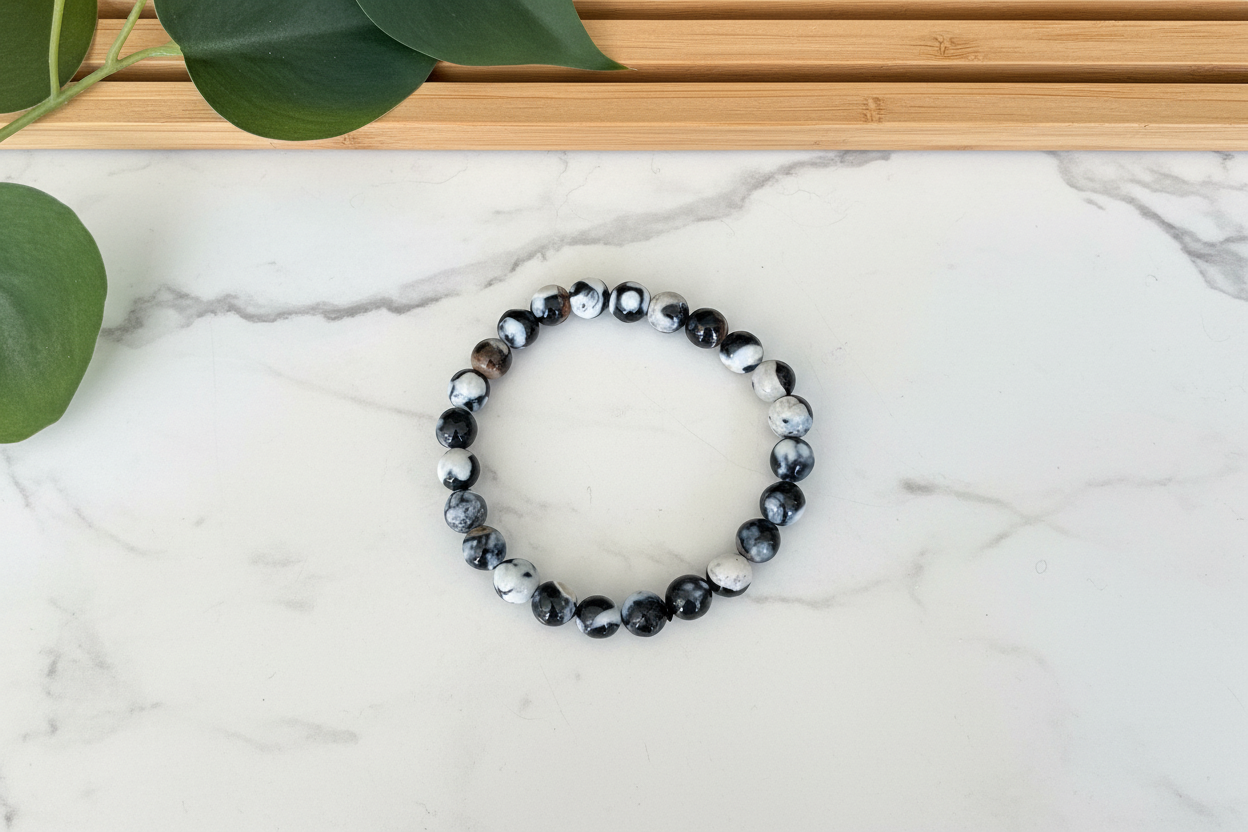 Black and white beaded bracelet on a white counter with a plant in the background