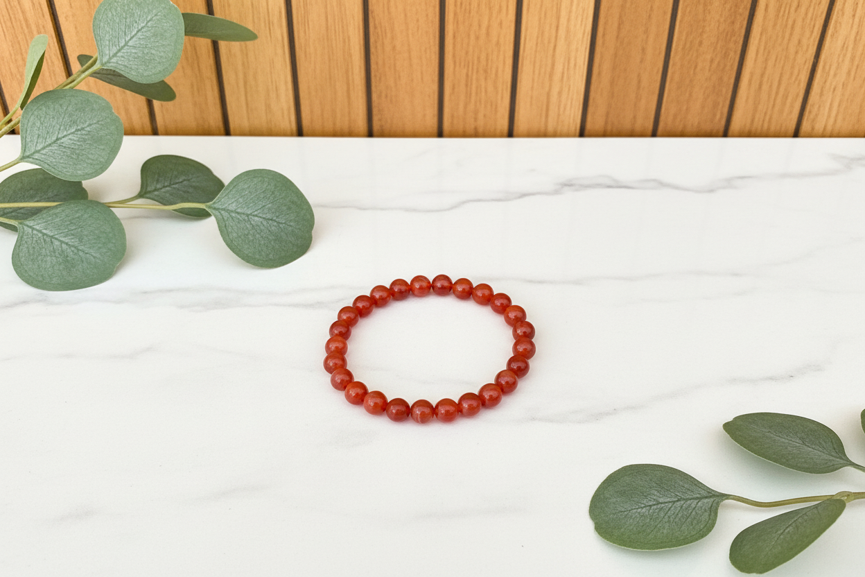 Red beaded bracelet on a white counter with a plant