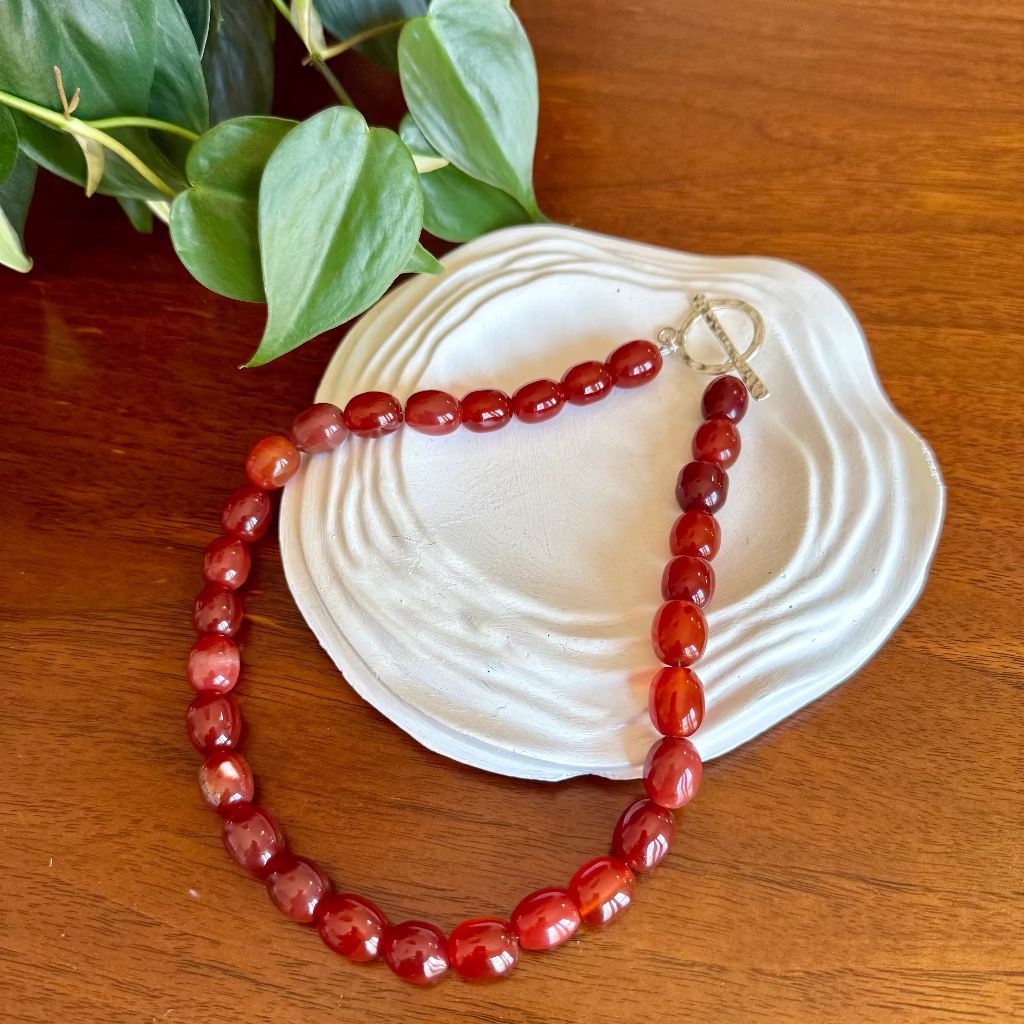 Red beaded necklace on a white ring dish
