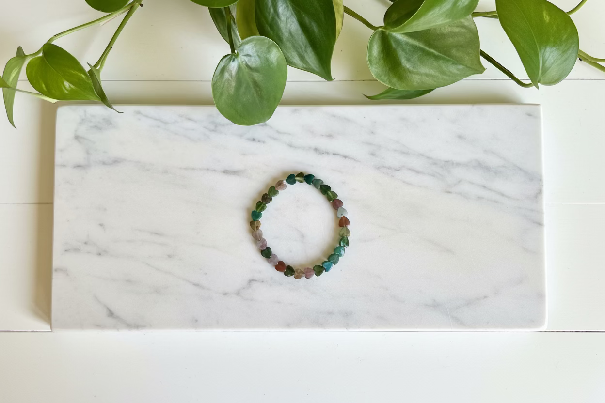Multicolored beaded bracelet on a white countertop with a plant in the background