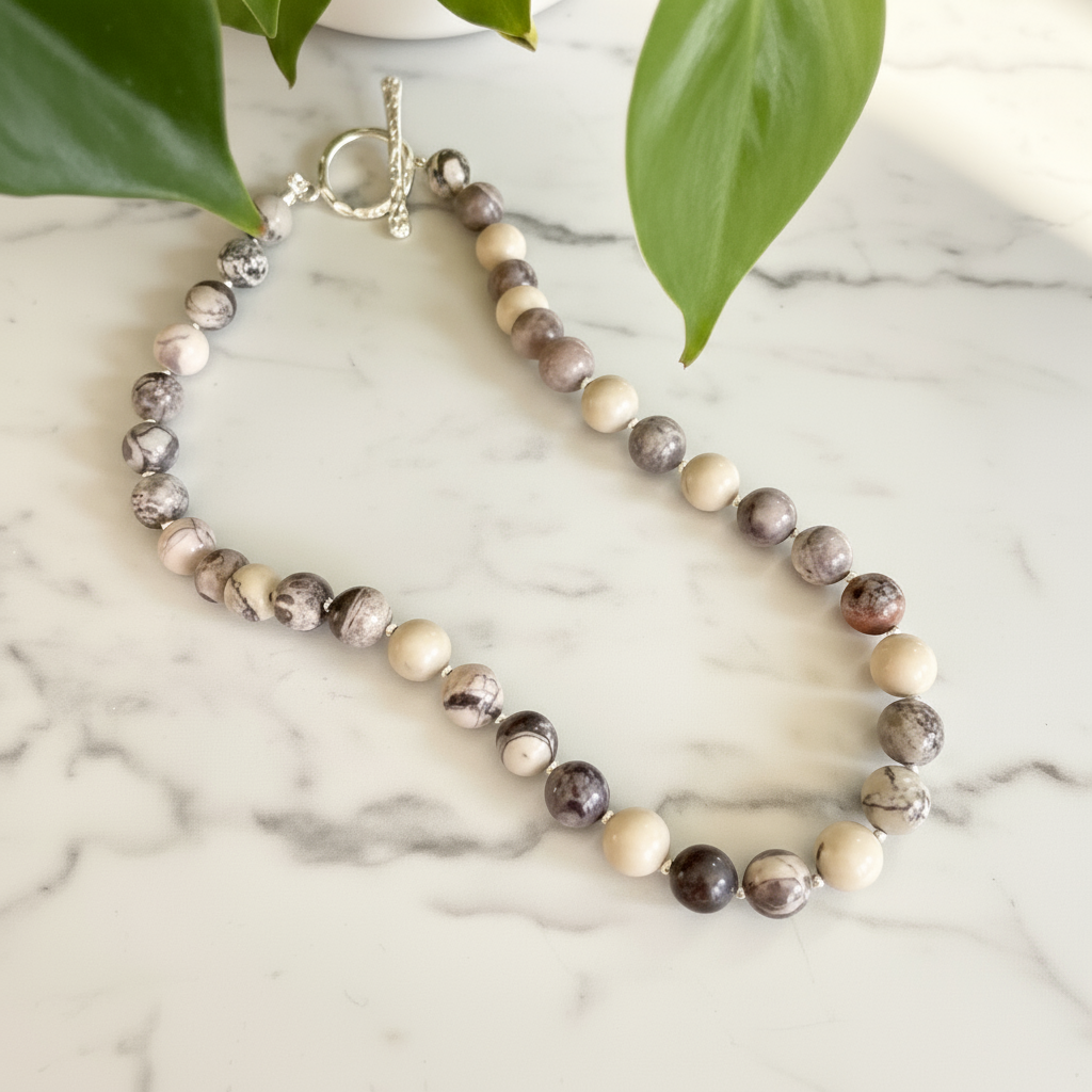 Jasper Gemstone Beaded necklace on a marble surface with green leaves