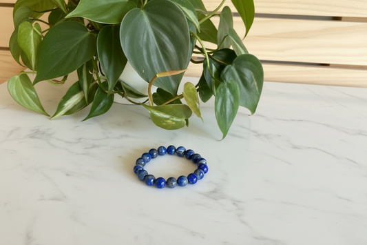 Blue beaded bracelet on a white counter with a plant in the background