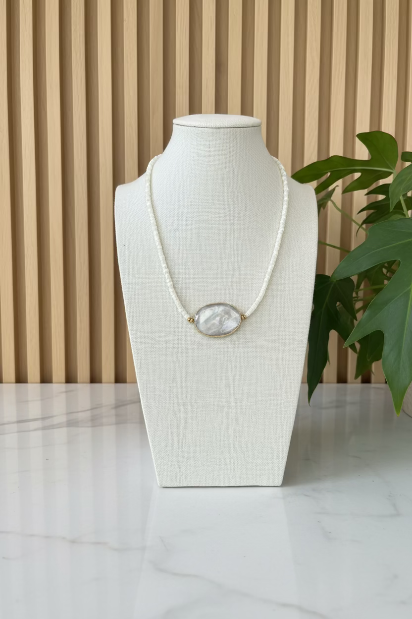 Necklace with a large central stone on a mannequin bust with plants in the background