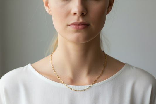 Gold paperclip chain necklace on a model in a white shirt