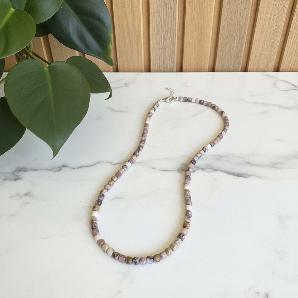 multi colored beaded necklace on a white countertop with a plant