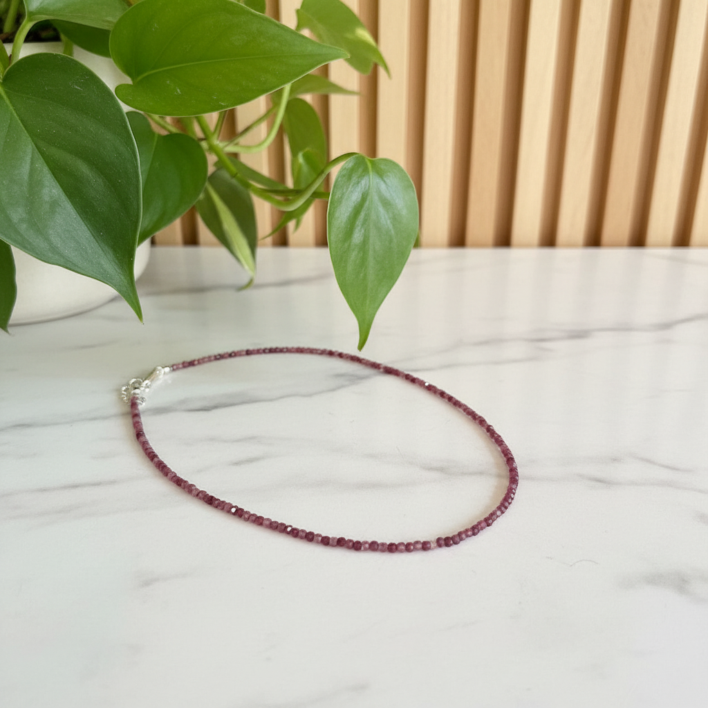 pink beaded necklace on a white counter with a plant in the background