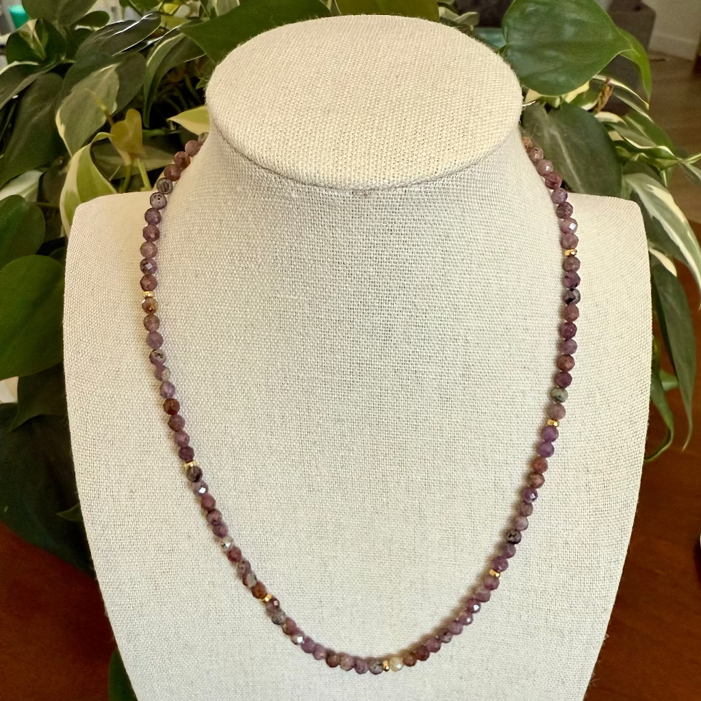 Necklace on a mannequin bust with a plant in the background