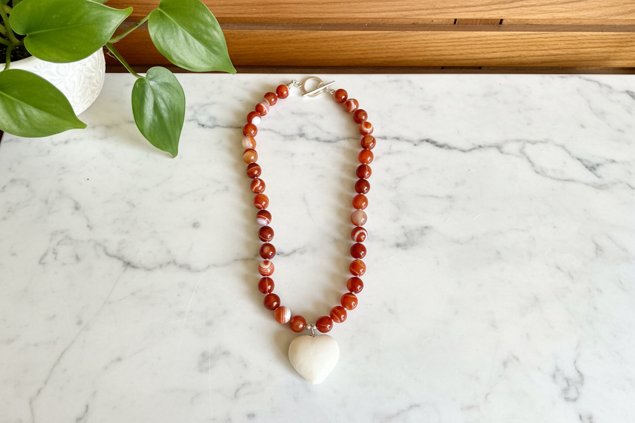 Necklace with red and white beads with a heart pendant on a white countertop