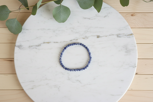 Blue beaded bracelet on a white counter with a plant in the background
