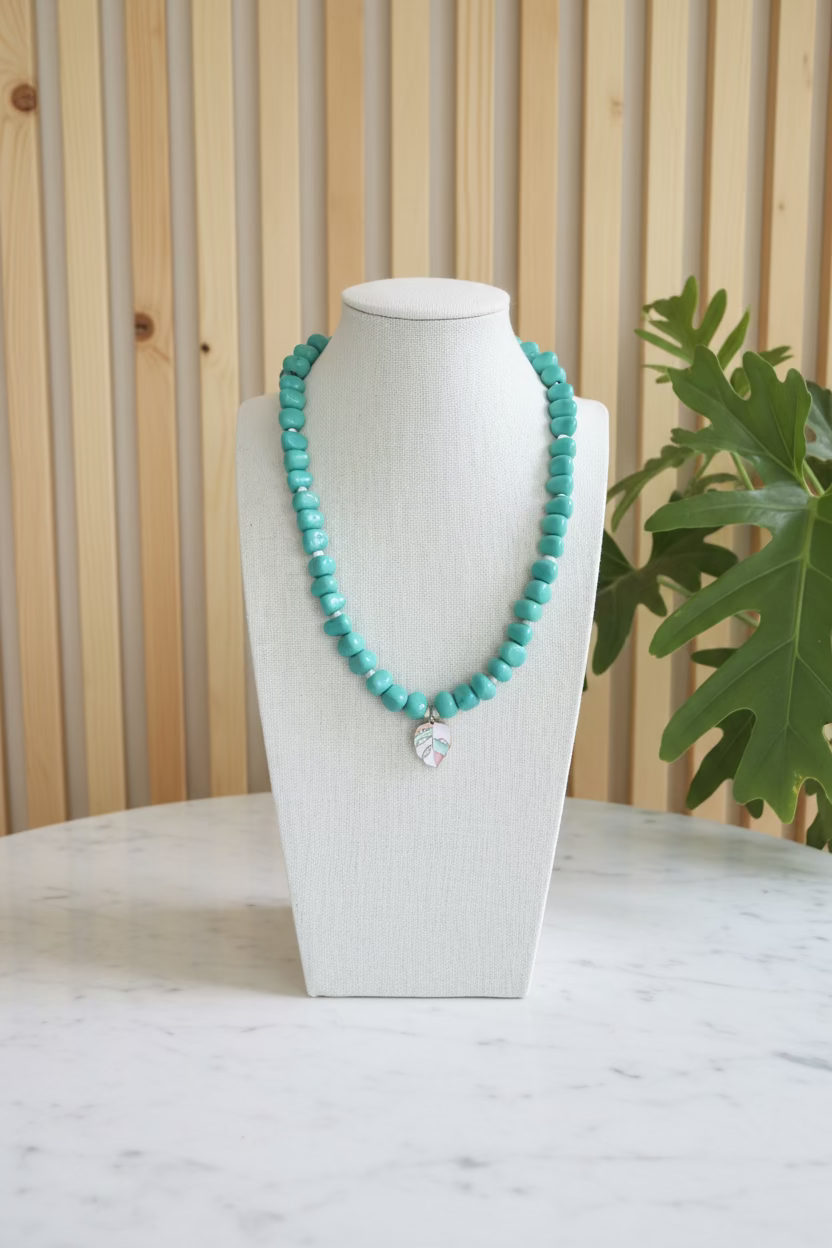 Turquoise beaded necklace on a mannequin bust with a plant and room background