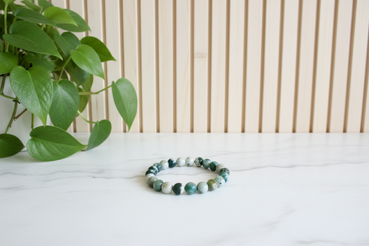 Green beaded bracelet on a white counter with a plant in the background