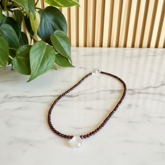 red beaded necklace on a white counter with a plant in the background