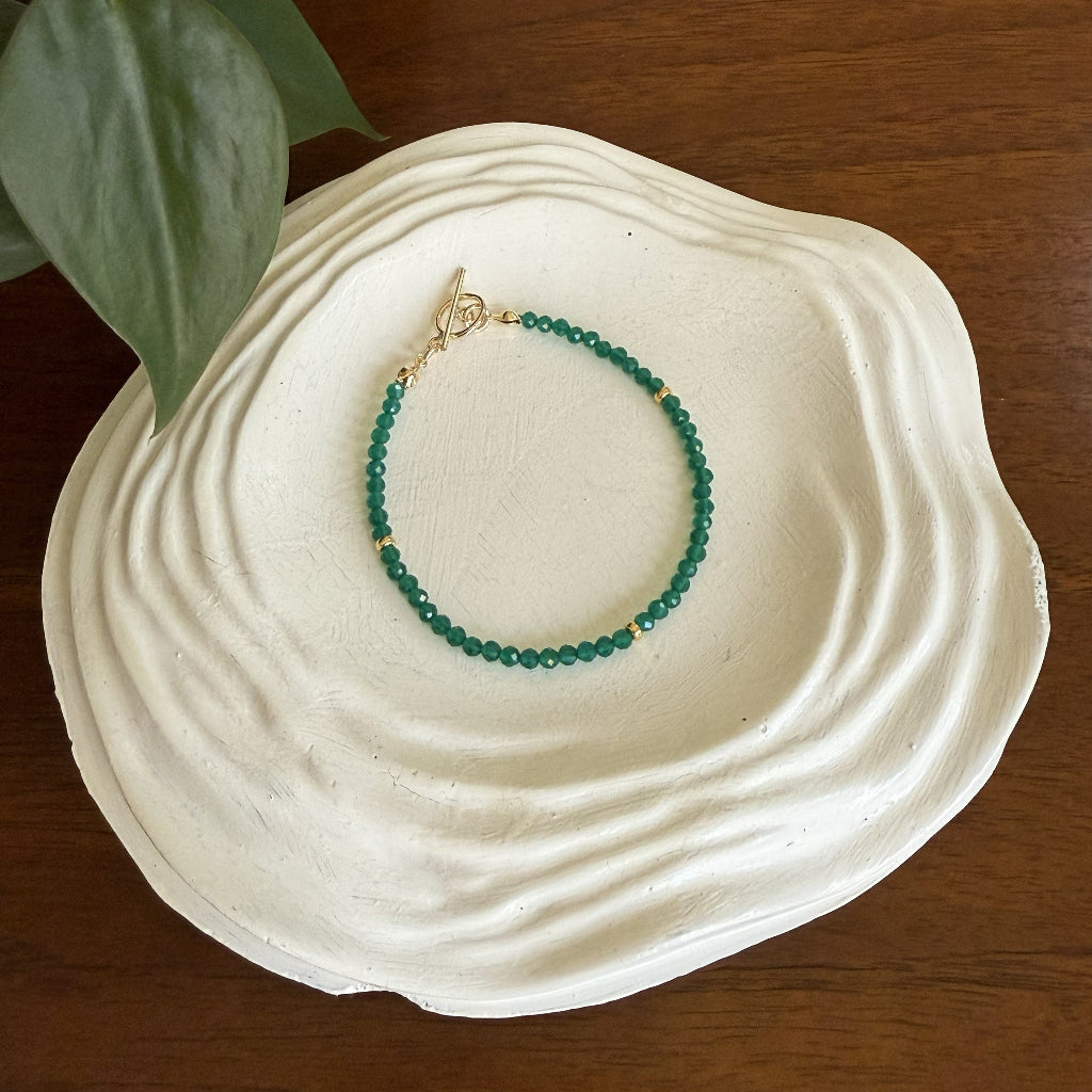 Green beaded bracelet on a white shell with a wooden background