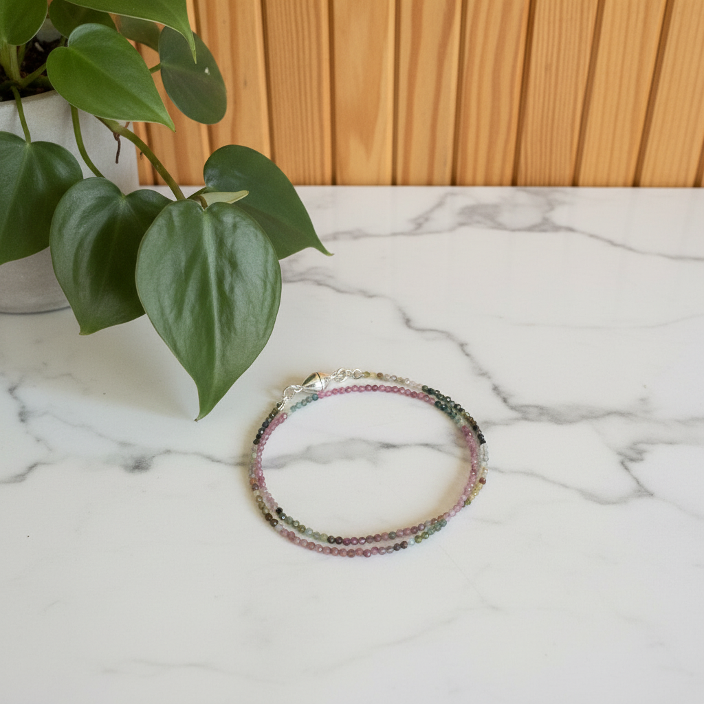 Multicolored beaded bracelet on a marble surface with a plant in the background