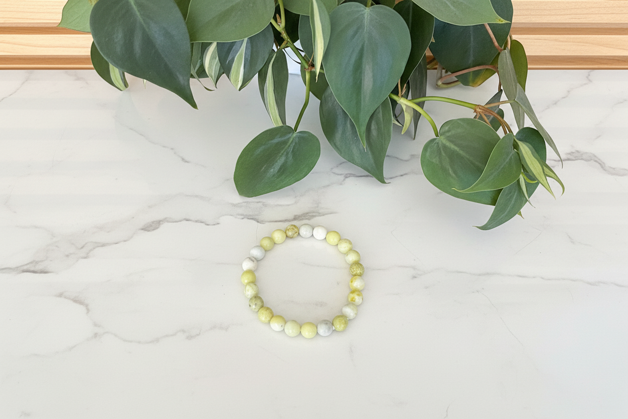 Yellow beaded bracelet on a white counter with a plant in the background