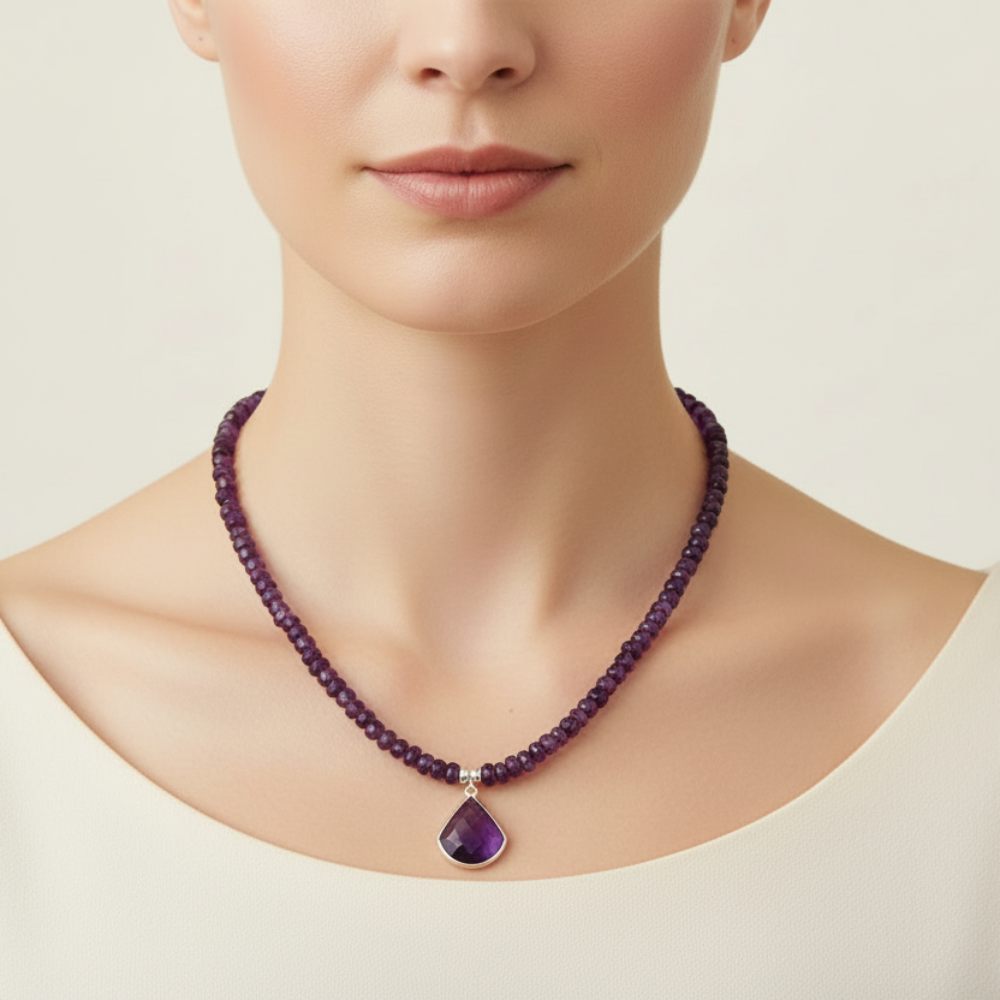 Woman wearing a purple amethyst beaded necklace with a purple pendant on a plain background