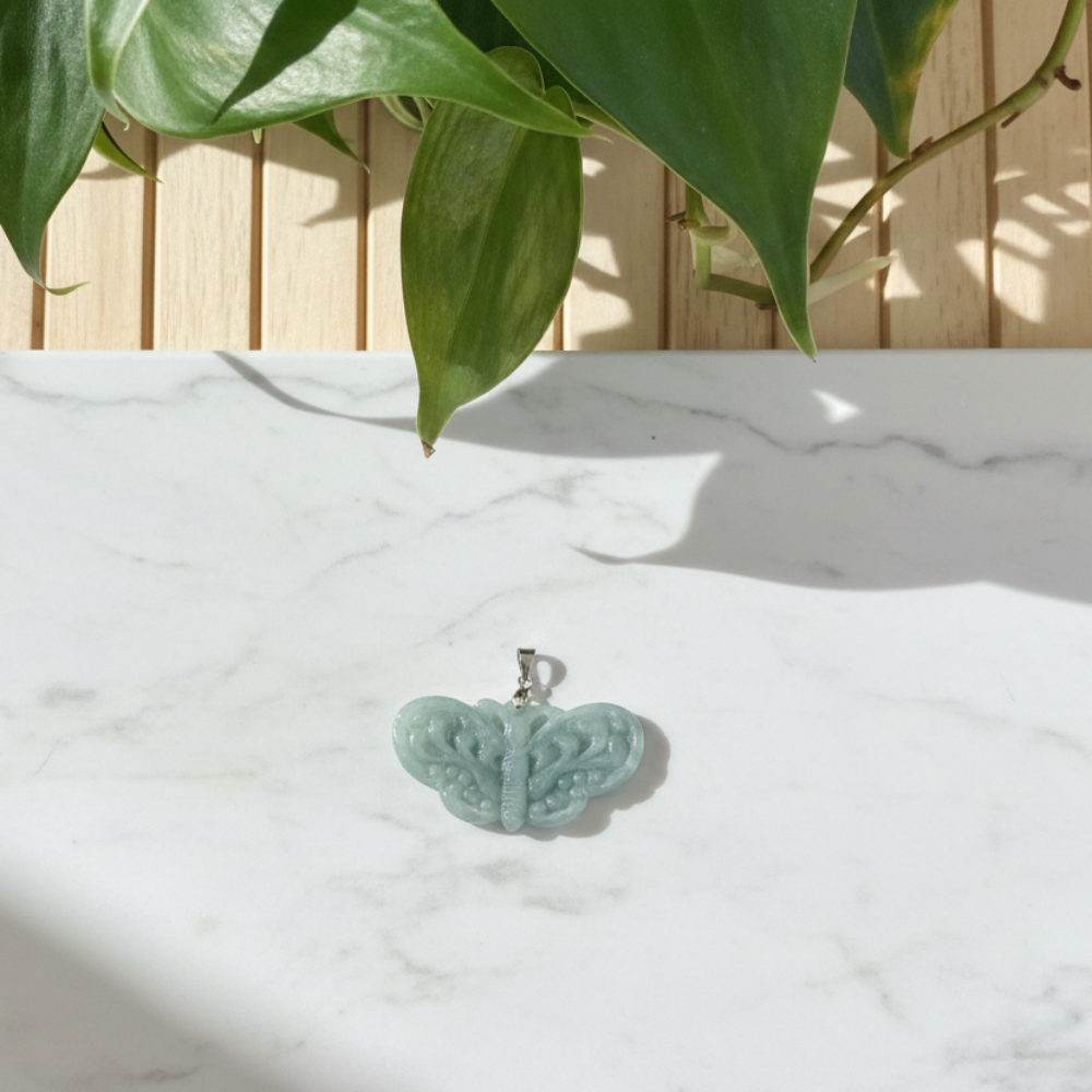 butterfly shaped pendant on a white marble countertop with a plant in the background