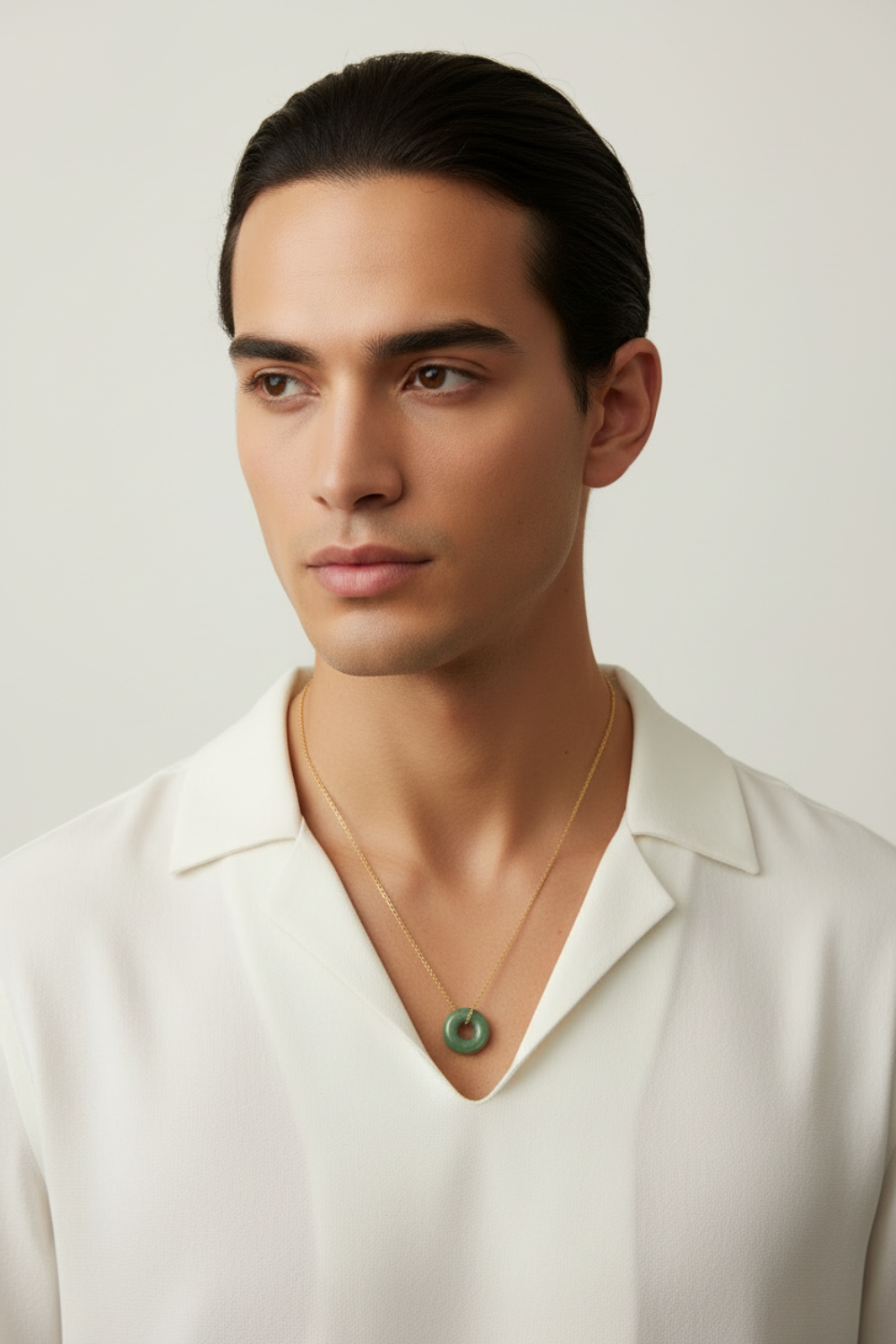Man wearing a white shirt and jade necklace with a neutral background
