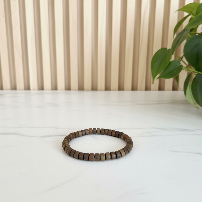 Green sandalwood beaded bracelet on a white marble counter with a plant in the background