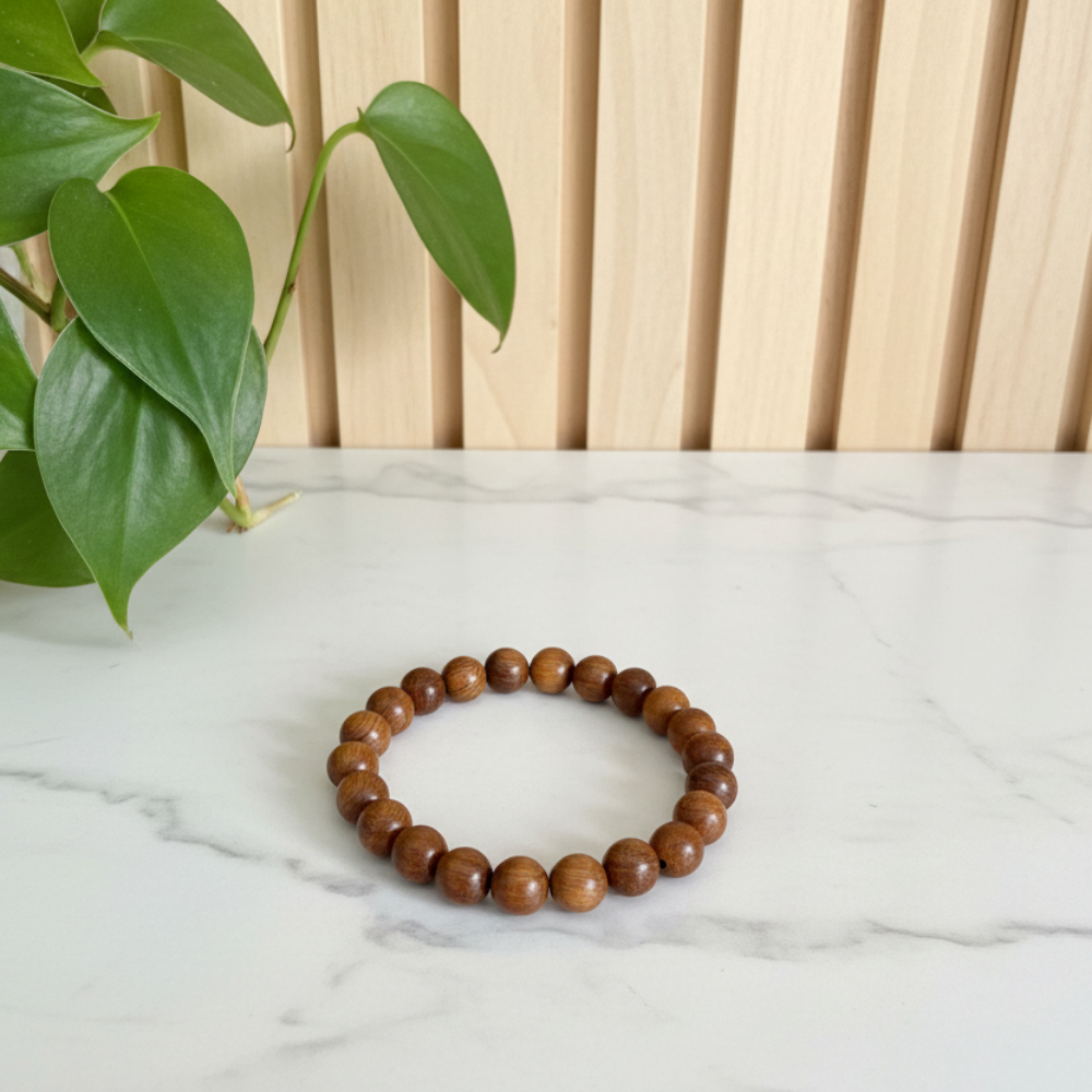 Sandalwood beaded bracelet on a white marble counter with green leaves in the background